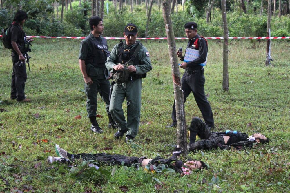 Policemen inspect bodies of suspected insurgents who were killed while attacking a military base in Narathiwat province, southern Thailand, Feb. 13, 2013.