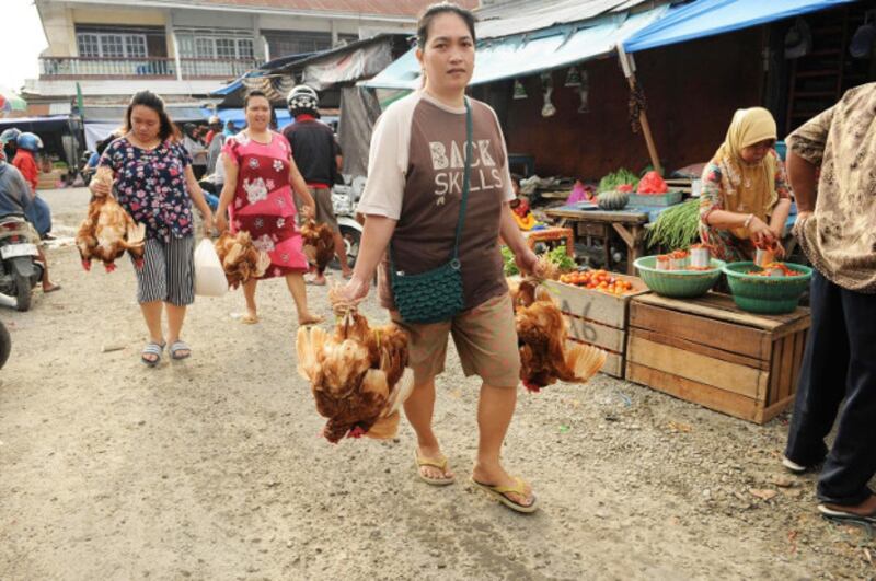Palu residents carry chicken they bought from a market which reopened days after a powerful quake and tsunami battered Indonesia's Central Sulawesi province, Oct. 4, 2018. [Keisyah Aprilia/BenarNews]