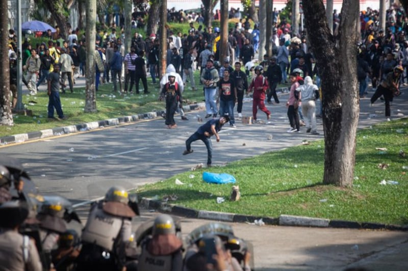 Dalam foto yang diambil pada 11 September 2023 ini, pengunjuk rasa melemparkan batu ke arah polisi saat berdemonstrasi di kantor Badan Usaha Batam di Provinsi Kepulauan Riau menentang rencana pemerintah untuk mengembangkan Pulau Rempang menjadi zona ekonomi yang didanai China yang akan menggusur sekitar 7.500 warga lokal. [Andaru/AFP ]