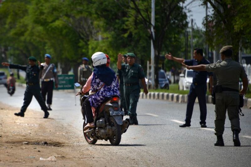 Anggota polisi Syariah menghentikan pengendara untuk pemeriksaan pakaian warga agar sesuai dengan aturan Syariah Islam di sepanjang jalan di Lambaro, Provinsi Aceh, 23 Juli 2019. [Chaideer Mahyuddin/AFP]
