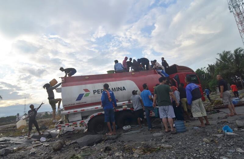 Sejumlah warga menjarah mobil pengangkut bahan bakar minyak yang melintas di Kota Palu, 1 Oktober 2018. (Yayank Stiv/BeritaBenar)
