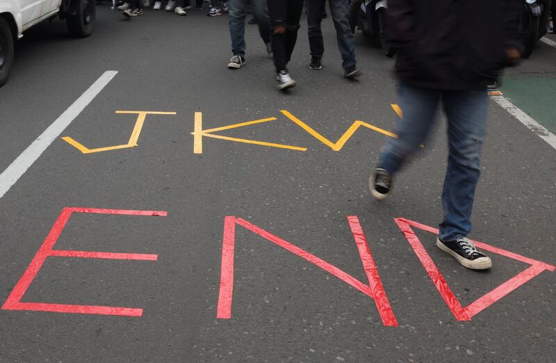 Mahasiswa berjalan melewati tulisan “JKW END” dalam unjuk rasa mengecam dugaan campur tangan Presiden Joko “Jokowi” Widodo dalam Pemilu 2024 di Jakarta, 7 Februari 2024. [Ajeng Dinar Ulfiana/Reuters]