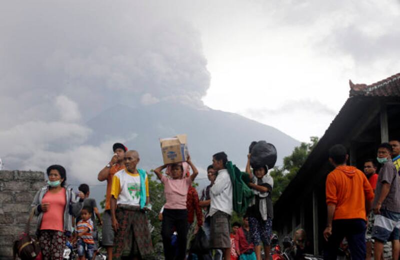 Sejumlah warga di Karangasem, Bali, mengungsi seiring dengan meletusnya Gunung Agung, terlihat di latar belakang, pada 26 November 2017.