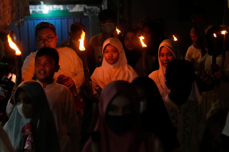 Anak-anak gembira ikut memeriahkan pawai obor pada malam hari menyambut datangnya Idulfitri di Jakarta, 1 Mei 2022. [AP]