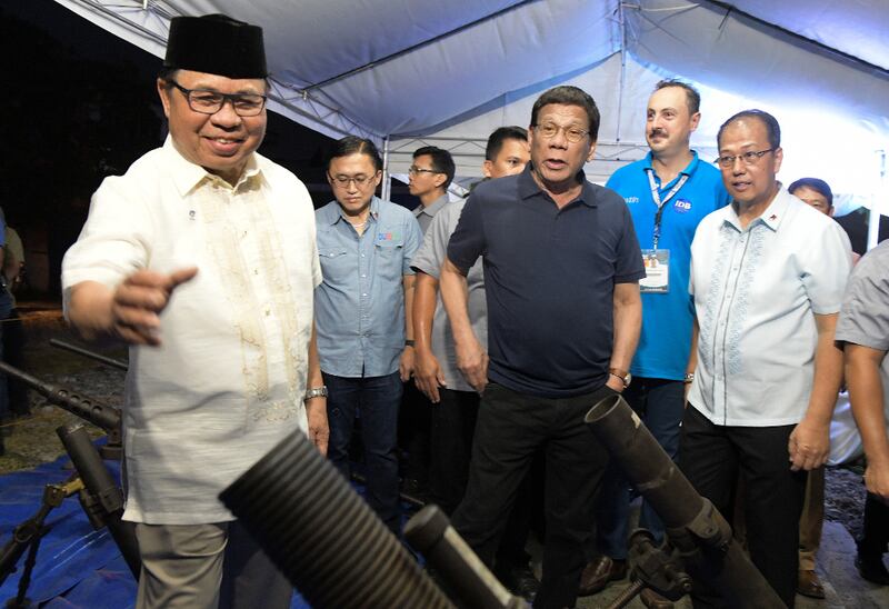 President Rodrigo Duterte (center) joins Moro Islamic Liberation Front leader Ebrahim Murad (left) in inspecting decommissioned firearms in Sultan Kudarat town, southern Philippines, Sept. 7, 2019. [Froilan Gallardo/BenarNews]