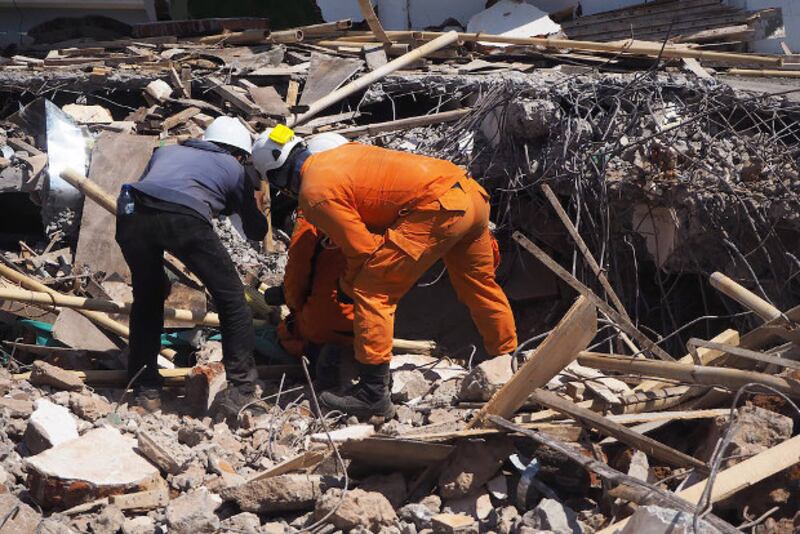 Rescuers search for survivors under concrete and twisted rebar of the Jabal Nur Mosque in Lading-Lading town of North Lombok, Indonesia, Aug. 7, 2018. [Anton Muhajir/BenarNews]