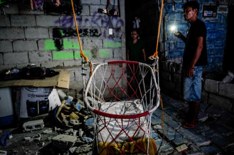 Janine Buan and her neighbor survey damage inside her house in Porac, Pampanga province, following Mnday's earthquake, April 23, 2019. (Jojo Rinoza/BenarNews)