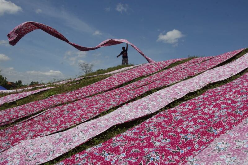 Seorang pekerja menjemur kain batik di kawasan industri di Sukoharjo, Jawa Tengah, 15 Juli 2021. [Antara Foto/Maulana Surya/via Reuters]