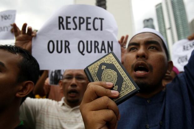Seorang lelaki Muslim memegang senaskhah al-Quran ketika dia melaungkan slogan semasa satu perhimpunan bantahan di luar Kedutaan Amerika Syarikat di Kuala Lumpur, Malaysia, 24 Feb 2012.