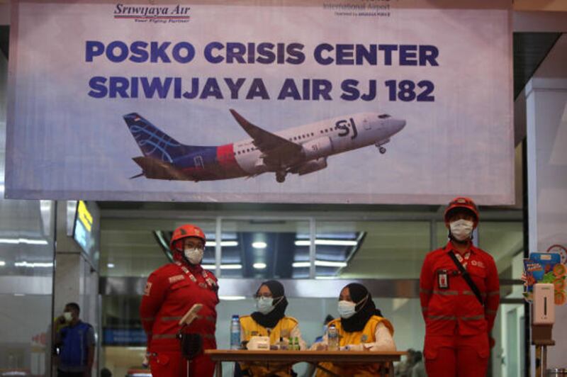 Sejumlah petugas berdiri di depan posko crisis center Sriwijaya Air SJ-182 di Bandara International Soekarno Hatta, Tanggerang, Banten, pada hari pesawat tersebut jatuh di sekitar perairan Kepulauan Seribu di Laut Jawa, 9 Januari 2021. [Araminta JR/BenarNews]