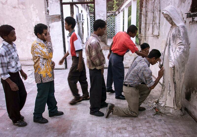 Dalam foto pada 17 Oktober 1999 ini, umat memberikan penghormatan kepada patung Bunda Maria yang rusak di rumah pemenang Hadiah Nobel Perdamaian, Uskup Carlos Belo, yang dibakar hingga hancur oleh milisi pro-Indonesia yang tidak puas dengan hasil referendum yang disponsori PBB di Dili, Timor Timur. [Charles Dharapak/AP]