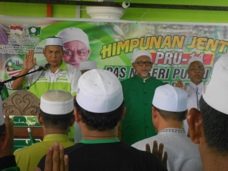PAS President Abdul Hadi Awang (center, in dark green top) stands with local PAS leaders at a partisan assembly in Permatang Pauh, Penang state, April 15, 2018. 