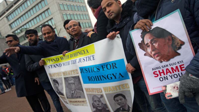 Demonstrators hold signs outside the International Court of Justice in The Hague, where Myanmar leader Aung San Suu Kyi attended the first day of three days of hearings, Dec. 10, 2019. [AP]