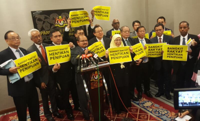 Opposition coalition members hold signs saying “Rise Up, People, and Stop the Fraud” at a press conference after parliament approved electoral redistricting, March 28, 2018.