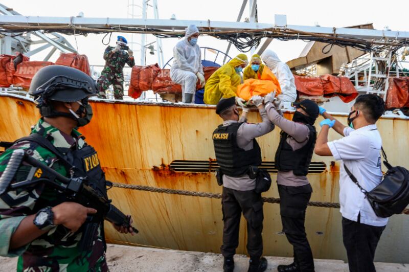 Dalam foto tertanggal 8 Juli 2020 ini, petugas menurunkan seorang mayat pekerja asal Indonesia yang meninggal saat bekerja di kapal penangkap ikan Cina, setelah kapal tersebut ditangkap di wilayah Batam, Kepulauan Riau. [AFP]