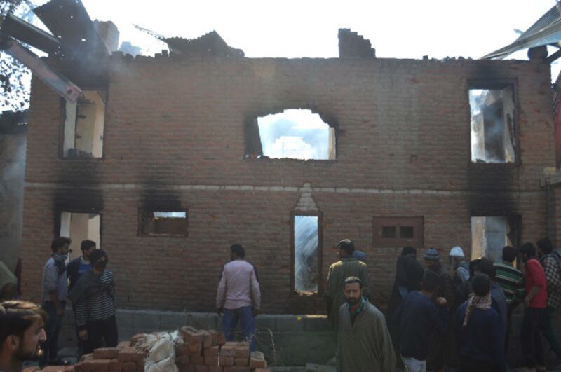 Local residents gather at a house that was damaged during a gunfight between Indian security forces and suspected militants in Laroo, a village in Kashmir's Kulgam district, Oct. 21, 2018.