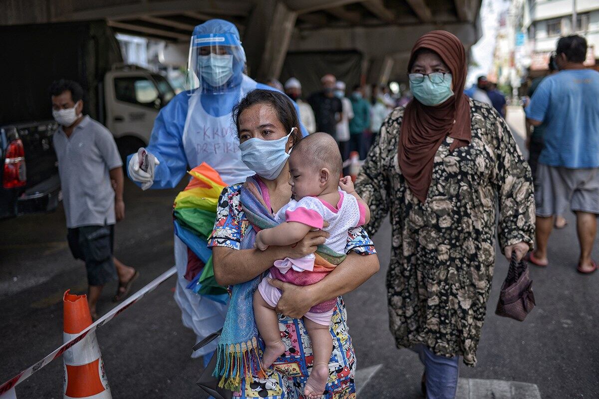 Seorang ibu warga asing mendukung anaknya berjalan menuju ke tempat ujian saringan COVID-19 di Pasar Pudu, Kuala Lumpur, 5 Mei, 2020.