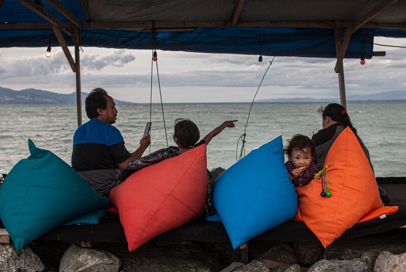 Sebuah keluarga bersantai dengan pemandangan laut di salah satu kafe yang dibangun di atas tanggul Teluk Palu di Pantai Talise, Palu, Sulawesi Tengah, Rabu, 15 Februari 2023. Kafe-kafe ini mulai beroperasi sejak sore pukul 15.00 WITA hingga tutup pukul 00.00 WITA setiap harinya. Menurut sejumlah penyintas, dengan kembali berjualan di lokasi ini, mereka merasa senang karena bisa mendapatkan penghasilan untuk menghidupi keluarga pasca musibah dahsyat 28 September 2018. Sebelum akhirnya bisa kembali beraktivitas di lokasi ini, penyintas bingung dan tidak tahu mau bekerja apa, sementara sebelum benca alam terjadi, mayoritas mereka adalah pedagang di kafe-kafe sepanjang pesisir Teluk Palu. [Taufan Bustan/BenarNews]