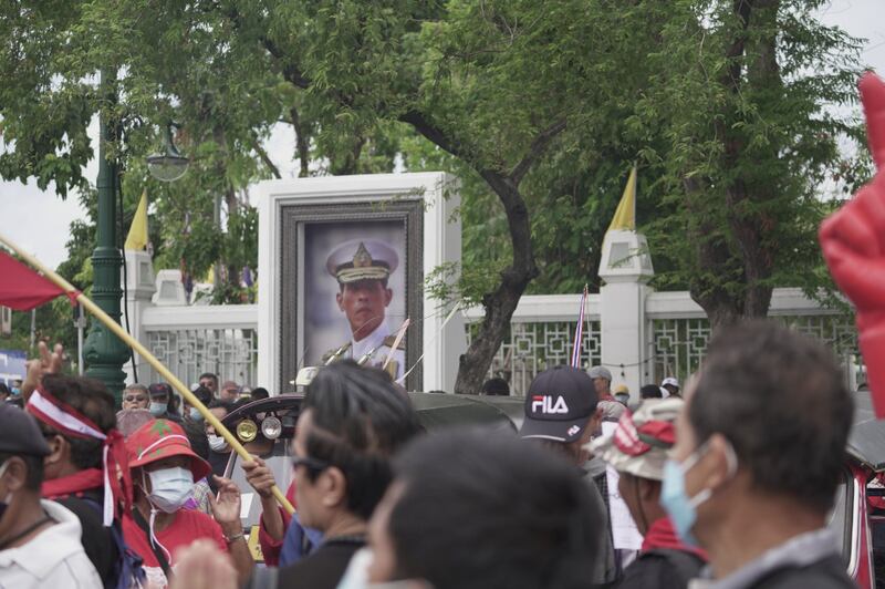 Anti-government protesters walk past a portrait of King Maha Vajiralongkorn in a Bangkok street, Sept. 19, 2020. [Nontarat Phaicharoen/BenarNews]