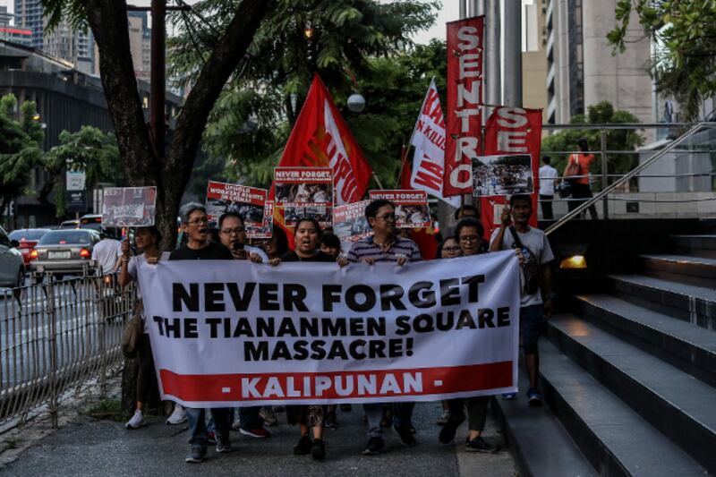 Demonstrators carry signs as they march past the Chinese Embassy in Manila's financial district to mark the 30th anniversary of the Tiananmen Square massacre, June 4, 2019. (Basilio Sepe/BenarNews)