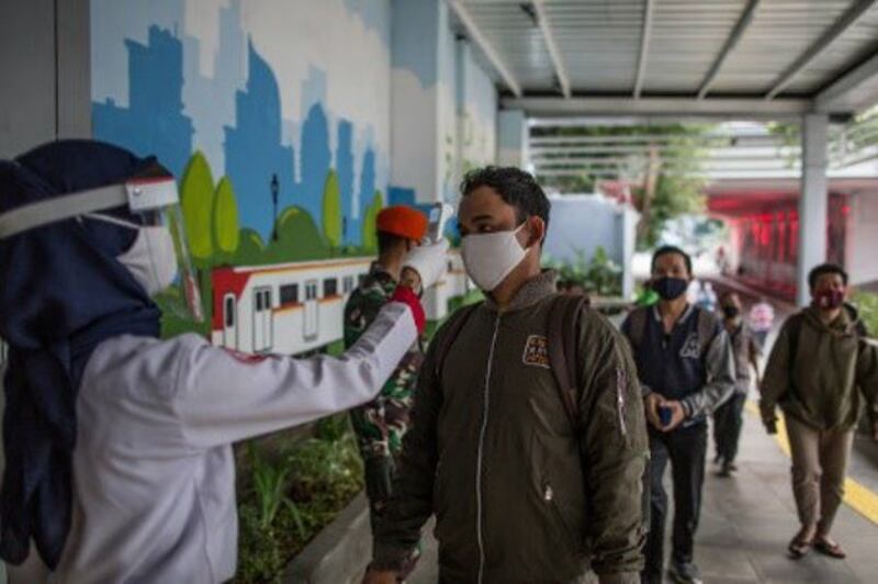 An official checks the body temperature of passengers at Jakarta's Sudirman Station, as the Indonesian capital loosened the two-month partial lockdown caused by the coronavirus pandemic, June 5, 2020. [Afriadi Hikmal/BenarNews]