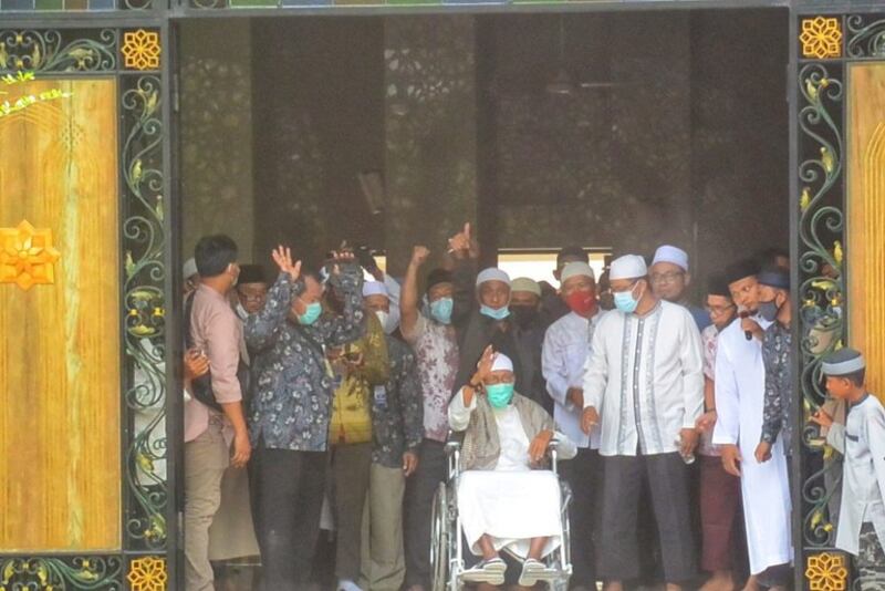 Ulama Abu Bakar Bashir, pemimpin spiritual kelompok militan Jemaah Islamiyah, melambai dari kursi roda saat tiba di Pondok Pesantren Al Mukmin dimana dia tinggal, dekat Solo (Surakarta), Jawa Tengah, setelah dibebaskan dari penjara karena beberapa dakwaan terkait terorisme, 8 Januari 2021. [Kusumasari Ayuningtyas/BenarNews]