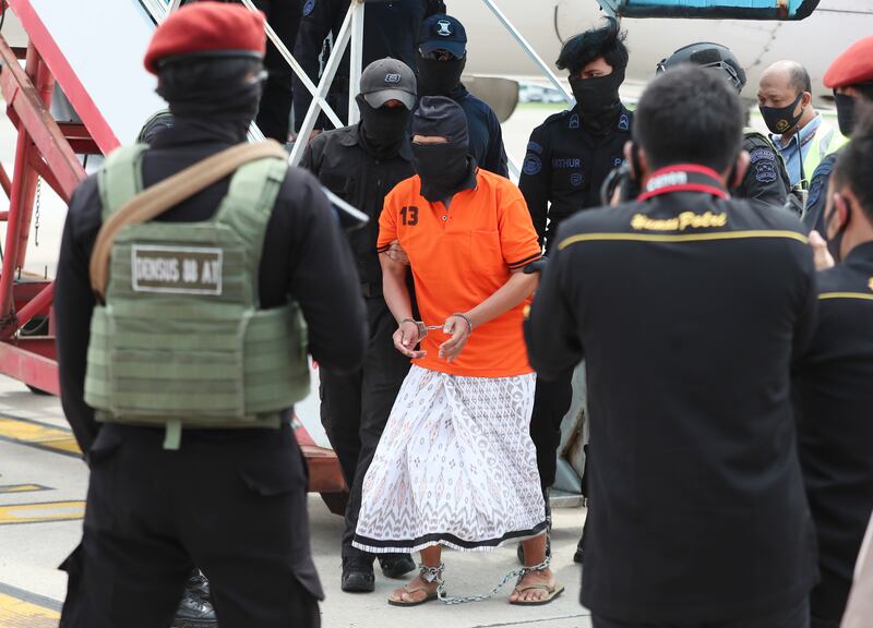 Polisi mengawal tersangka salah satu pimpinan jaringan Jemaah Islamiyah, Zulkarnaen (tengah), yang juga dikenal sebagai Aris Sumarsono, setibanya di Bandara Internasional Soekarno-Hatta di Tangerang, Banten, 16 Desember 2020. [AP]