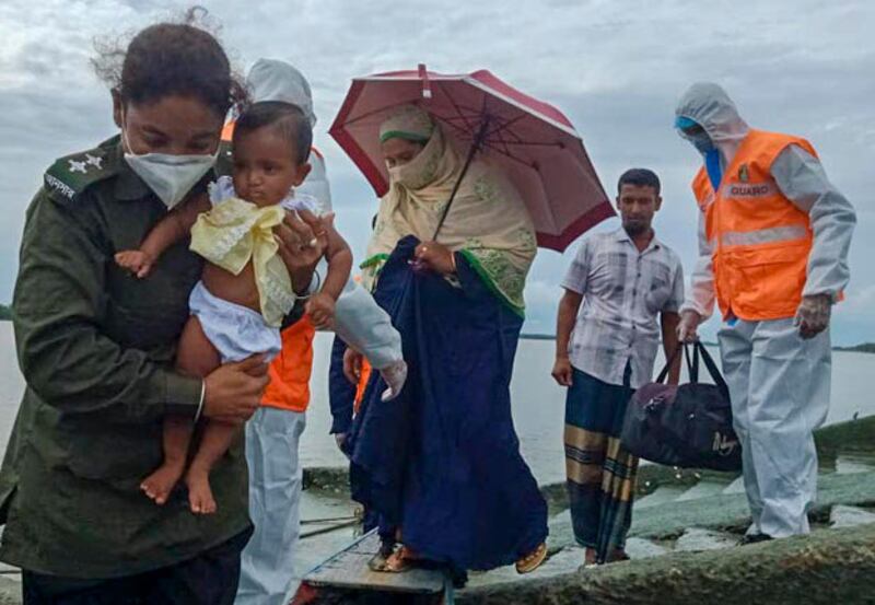 A Bangladesh paramilitary member carries a baby as she assists a family heading to an evacuation center in the Satkhira district of Bangladesh, May 20, 2020. [BenarNews]
