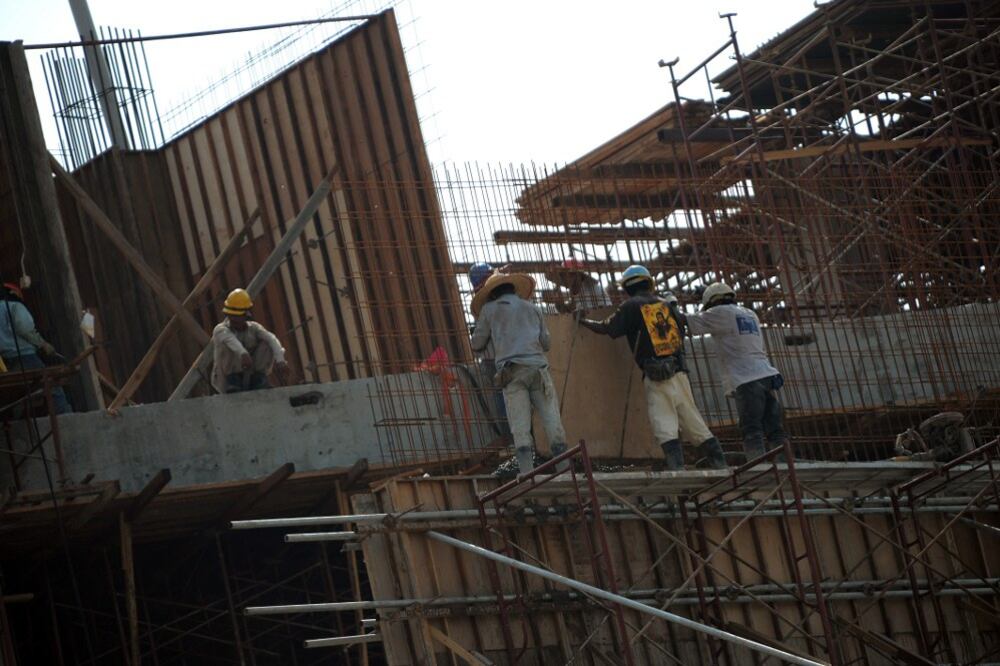 Beberapa buruh sedang menjalankan kerja di atas bumbung sebuah tapak pembinaan di Kuala Lumpur, 13 Mei 2010.