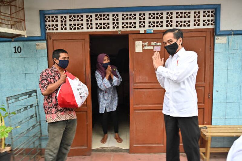 Presiden Joko Widodo mengucapkan salam setelah memberikan paket sembako ke warga yang terdampak pandemi COVID-19 di Jakarta, 18 Mei 2020. [AFP]