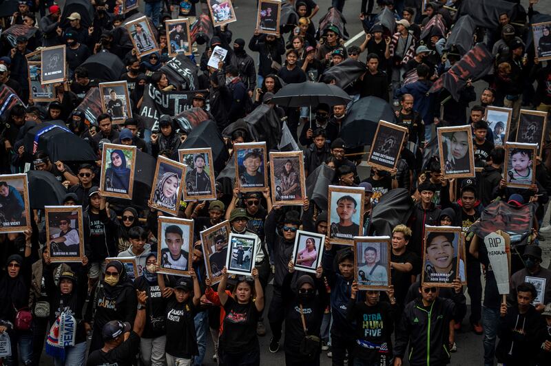 Membawa foto-foto korban yang meninggal, warga berunjuk rasa di depan Balai Kota Malang pada 10 November 2022, menuntut Persatuan Sepak Bola Seluruh Indonesia (PSSI) bertanggung jawab, adil dan transparan dalam melakukan investigasi menyusul insiden maut di Stadion Kanjuruhan pada 1 Oktober 2022 yang memakan 135 korban jiwa. [Juni Kriswanto/AFP]