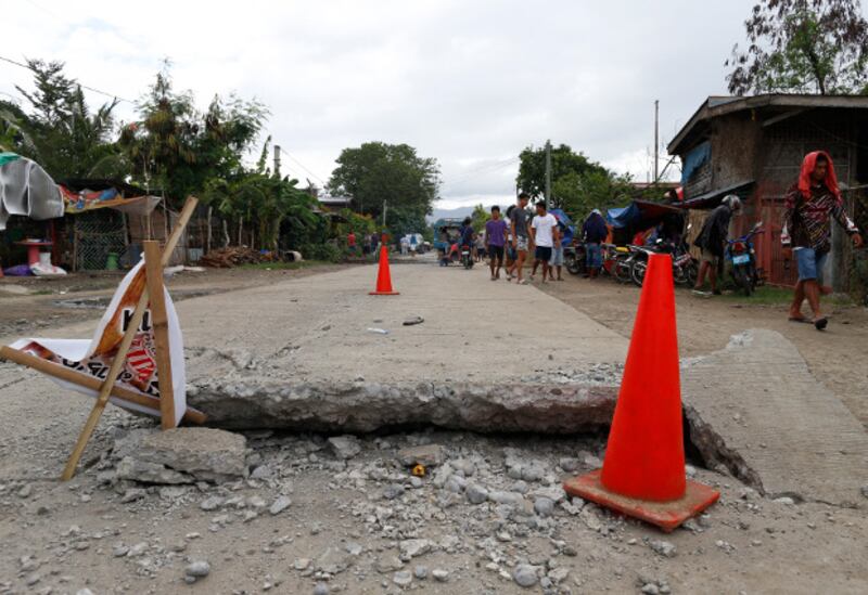Residents walk along a destroyed road in Padada town in the southern Philippine province of Davao del Sur after a 6.9-magnitude earthquake, Dec. 16, 2019. [Jeoffrey Maitem/BenarNews]