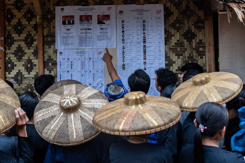 Anggota suku asli Baduy memeriksa daftar para kandidat yang bertarung dalam Pemilu 2024 di sebuat TPS di Desa Kanekes, Lebak, provinsi Banten pada 14 Februari 2024. [Aditya Aji/AFP]