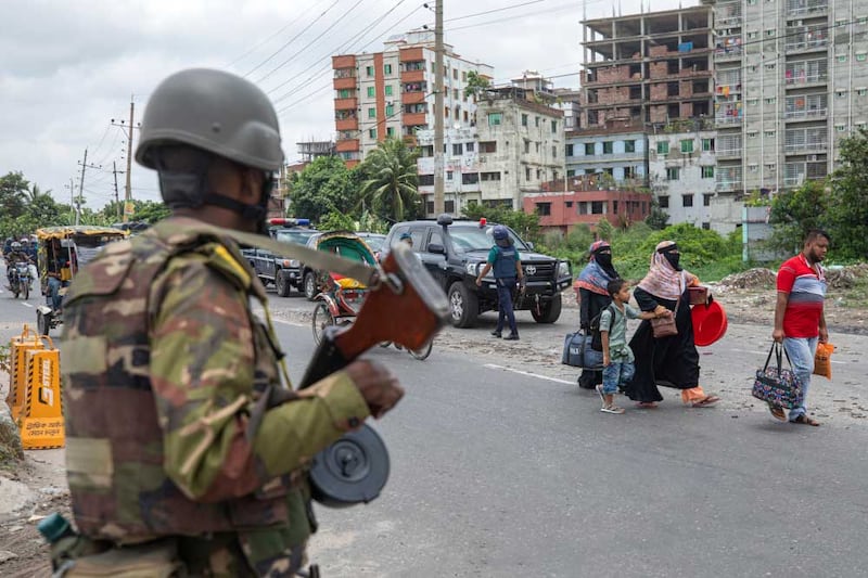 Bangladesh police inspect a motorcyclist's bag during a traffic stop in Dhaka on the fourth day of curfew imposed by the government, July 23, 2024. [Rajib Dhar/AP]