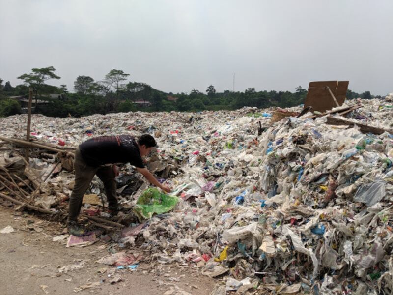 Seorang laki-laki mengambil sebuah bungkus plastik di sebuah lokasi pembuangan sampah plastik di Bekasi, 16 Mei 2019. (Ahmad Syamsudin)
