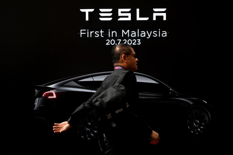 Seorang lelaki berjalan di depan kain rentang Tesla semasa pelancaran sulung kereta elektrik firma itu di Malaysia di Kuala Lumpur, 20 Julai 2023. [Mohd Rasfan/AFP]