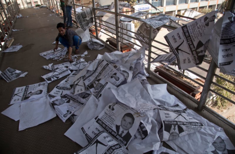 A Bangladeshi man collects election posters in Dhaka, a day after the ruling coalition won almost every seat in parliament through the country's 11th general election, Dec. 31, 2018. [AP]