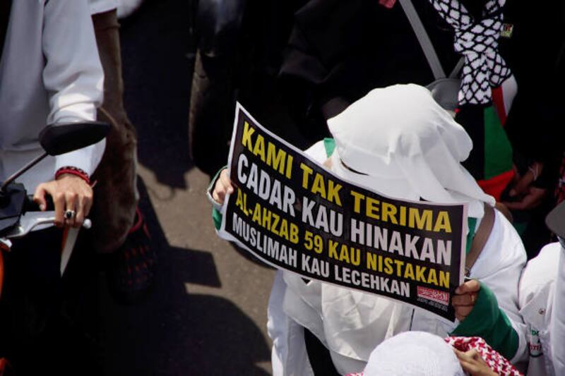 Seorang perempuan membawa poster saat aksi unjuk rasa di Jakarta, 6 April 2018. (Arie Firdaus/BeritaBenar)