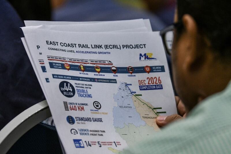 A journalist reads a handout on the East Coast Rail Link project distributed at a press conference in Putrajaya, Malaysia. April 15, 2019. [S. Mahfuz/BenarNews]