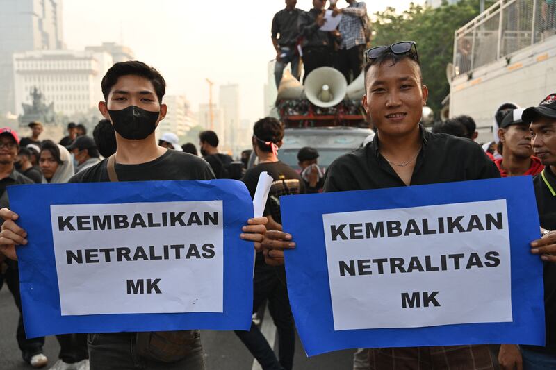 Aktivis memegang poster saat melakukan protes terhadap keputusan Mahkamah Konstitusi yang merubah peraturan batas minimum umur kandidat presiden/wakil presiden yang memuluskan pencalonan Gibran Rakabuming Raka, putra Presiden Joko Widodo, menjadi cawapres mendampingi capres Prabowo Subianto yang juga adalah menteri pertahanan, di Jakarta, 26 Oktober 2023. [Adek Berry/AFP]