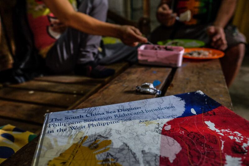 A book about an international court case in a territorial dispute over Scarborough Shoal sits on a bench in Johnny Sonny Geruela's home as he and his wife share a meal, Sept. 6, 2019. [Jojo Rinoza/BenarNews]