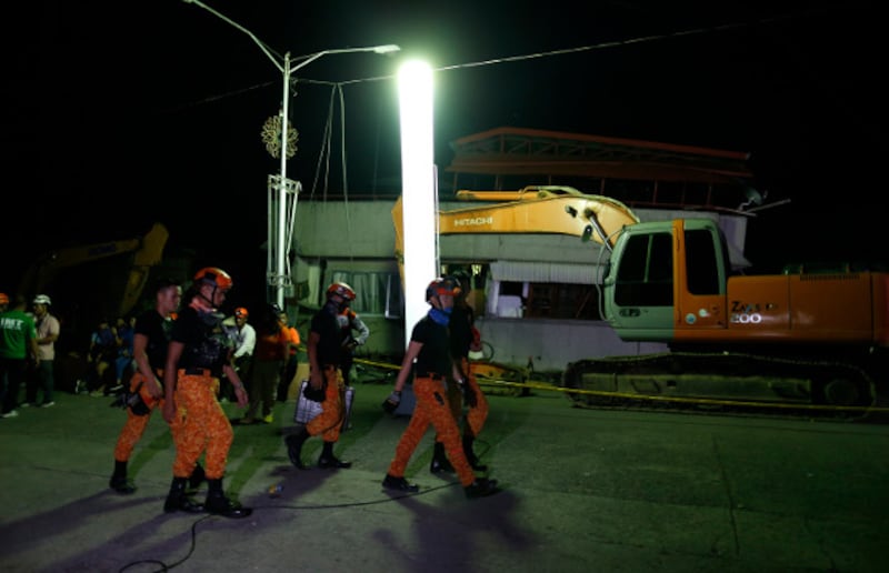 Rescuers walk near a building that collapsed in Padada town in the southern Philippine province of Davao Del Sur following a 6.9-magnitude earthquake, Dec. 16, 2019. [Jeoffrey Maitem/BenarNews]