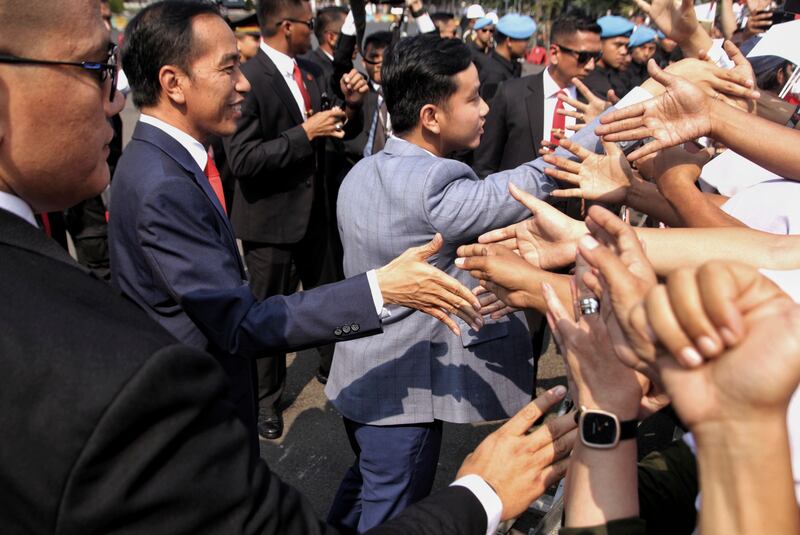 Presiden Joko Widodo dan putranya, Gibran Rakabuming Raka, menyambut para pendukungnya sebelum pelantikan masa jabatan keduanya, di Jakarta, 20 Oktober 2019. [AP]