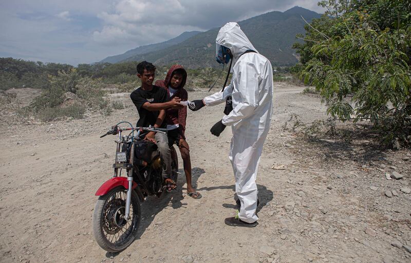 Seorang warga yang tergabung dalam Koalisi Petisi Palu-Donggala menggunakan alat pelindung diri saat memberikan masker kepada dua pengendara sepeda motor yang melintas saat menggelar aksi unjuk rasa di lingkar tambang galian C Kelurahan Buluri, Palu, Sulawesi Tengah, 21 Mei 2024. [Taufan Bustan/BenarNews]