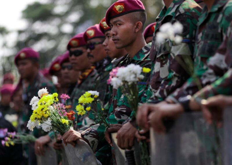 Pasukan marinir yang berjaga di sekitar gedung parlemen memegang bunga yang diberikan oleh para mahasiswa yang berunjuk rasa di Jakarta, 1 Oktober 2019. (AP)