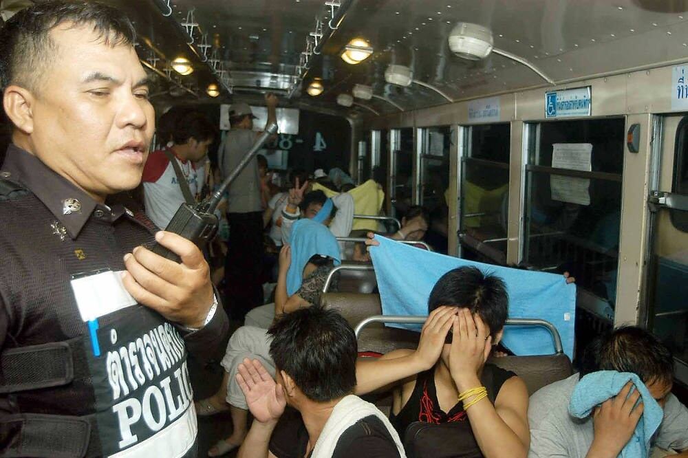 North Koreans refugees who entered the country illegally are escorted by a Thai policeman to an immigration office in Bangkok, Aug. 22, 2006.