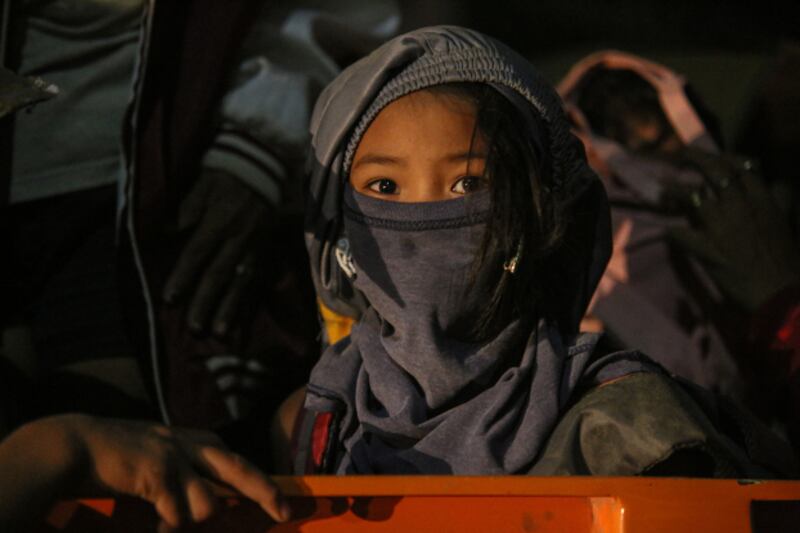 A young girl covers her head and face as her family evacuates from the danger zone near the Taal Volcano, Jan. 12, 2020. [Jojo Riñoza/BenarNews]