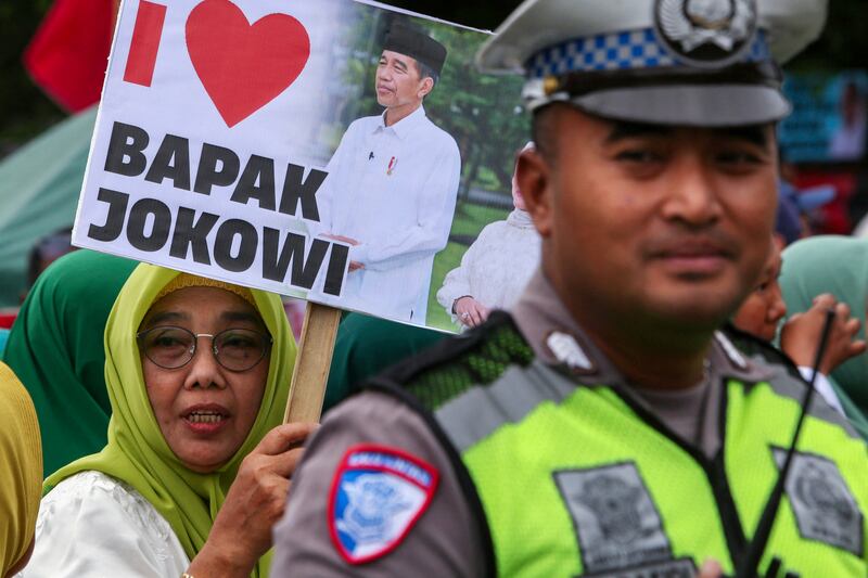 Seorang warga memegang poster saat ia dan ribuan orang lainnya menyambut kepulangan mantan Presiden Indonesia Joko Widodo ke kampung halamannya di Solo, Jawa Tengah, 20 Oktober 2024. [Devi Rahman/AFP]