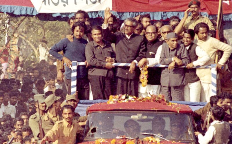 নয় মাস পাকিস্তানের জেলে কাটিয়ে স্বাধীন দেশে প্রত্যাবর্তনের পর মোটর শোভাযাত্রা থেকে জনতাকে অভিনন্দন জানাচ্ছেন বাংলাদেশের প্রতিষ্ঠাতা শেখ মুজিবুর রহমান। তাঁর বামপাশে মুজিবনগর সরকারের প্রধানমন্ত্রী তাজউদ্দীন আহমেদ। ৭৫'র আগস্ট শেখ মুজিব হত্যার পর নভেম্বরে তাজউদ্দীন আহমেদসহ চার জাতীয় নেতাকে ঢাকা কেন্দ্রীয় কারাগারে হত্যা করা হয়। ১০ জানুয়ারি ১৯৭২। [এপি]