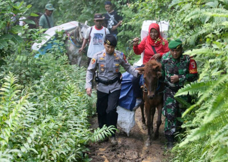 Polisi dan tentara ikut menjaga kotak suara yang diangkut dengan kuda ke TPS-TPS di sejumlah desa di Tempurejo, Jawa Timur, 15 April 2019. (AP)
